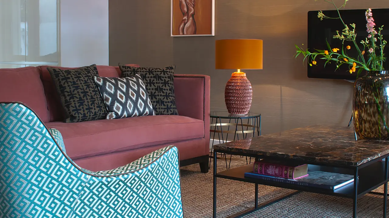 Roze bank met grafische kussens en een turquoise fauteuil met dessin