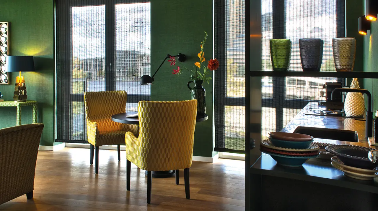 Eethoek met gele stoelen bij het raam en een kast met servies