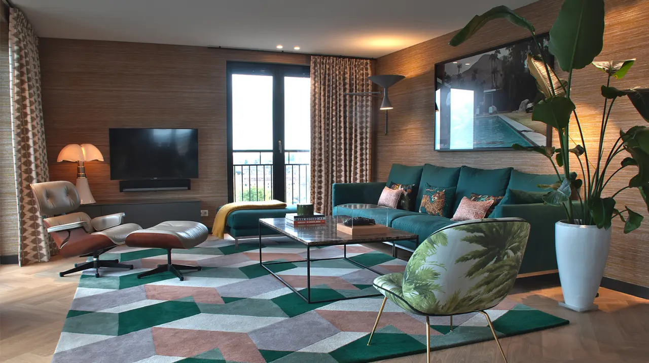 Woonkamer met groene bank, grafisch vloerkleed en grote planten