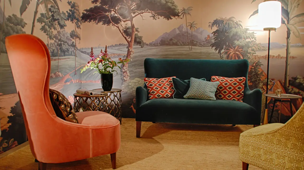 Oranje fauteuil en groene bank voor een wandschildering met landschap